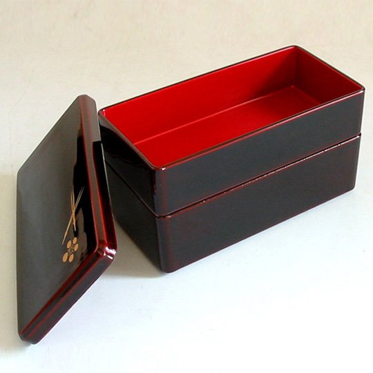 Two-tier Isuke lacquered bento box in red, featuring plum motif, designed for Japanese-style lunches
