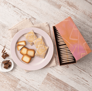 “Assortment of Yoku Moku Double Chocolat Au Lait cookies arranged beside tin”
